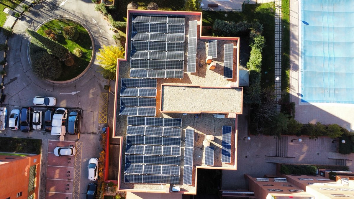 Placas solares cubriendo la azotea de un bloque de viviendas con piscina comunitaria